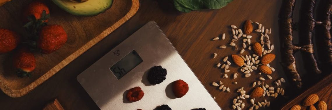 Top view of composed raw almond with seeds and avocado on table with berries on scales for cooking healthy dish